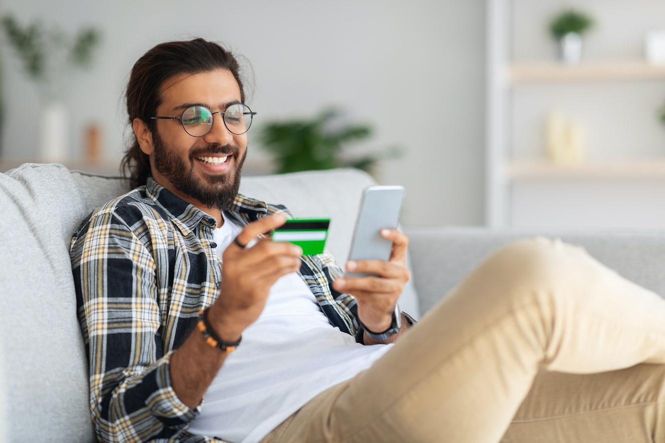 Cheerful person with credit card and phone