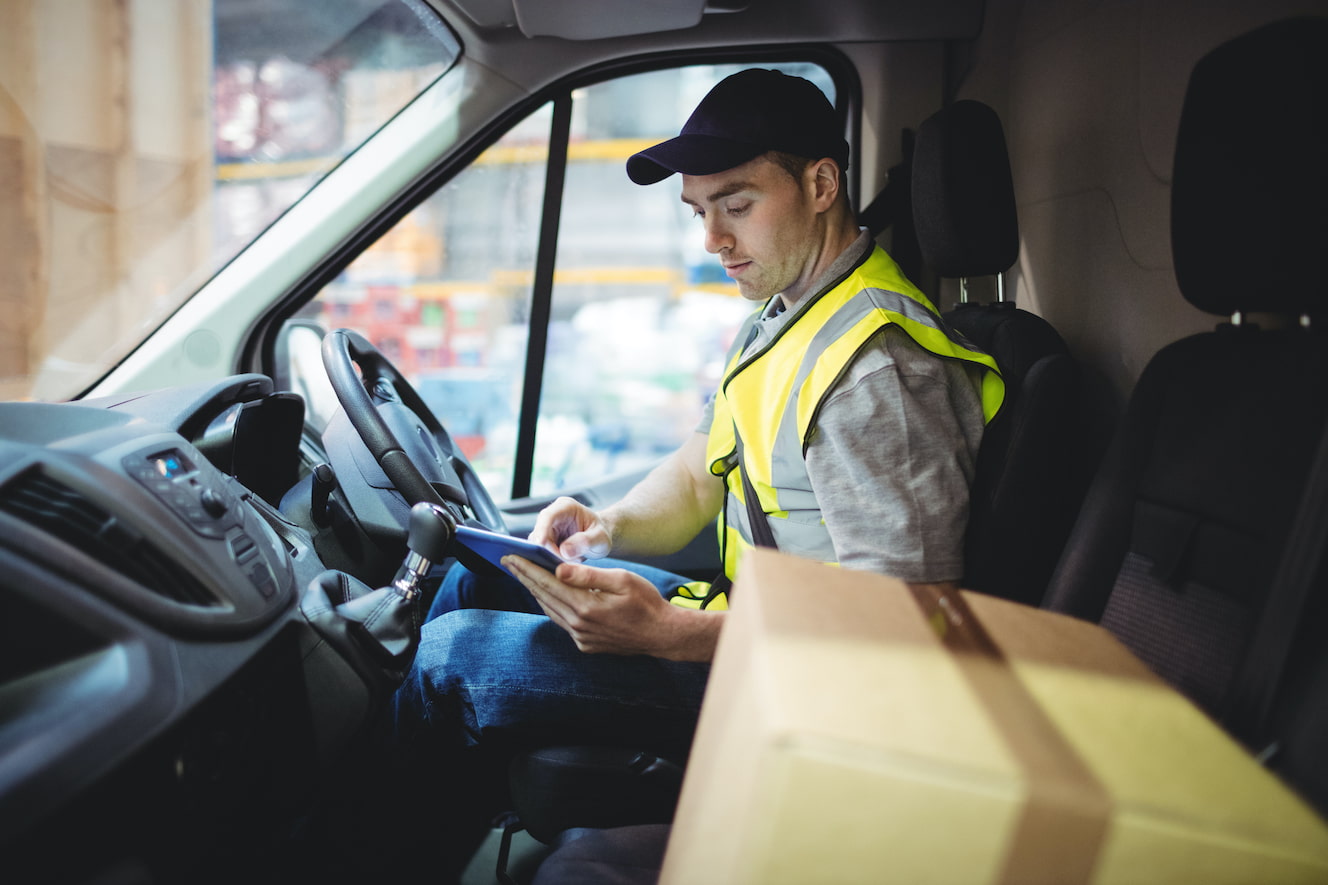 Delivery Driver in Vest Looking at Tablet