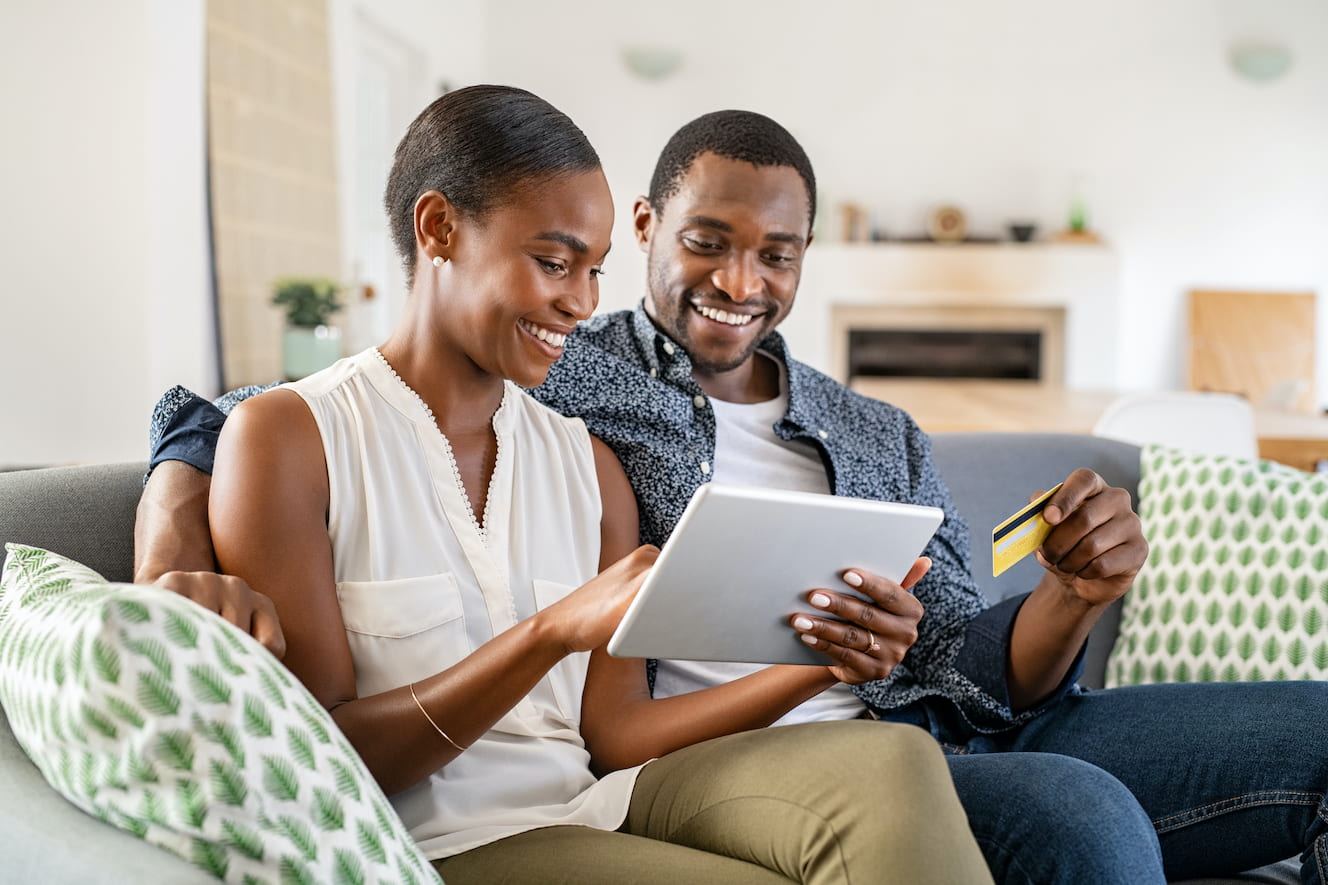 Smiling people sitting on couch looking at tablet together