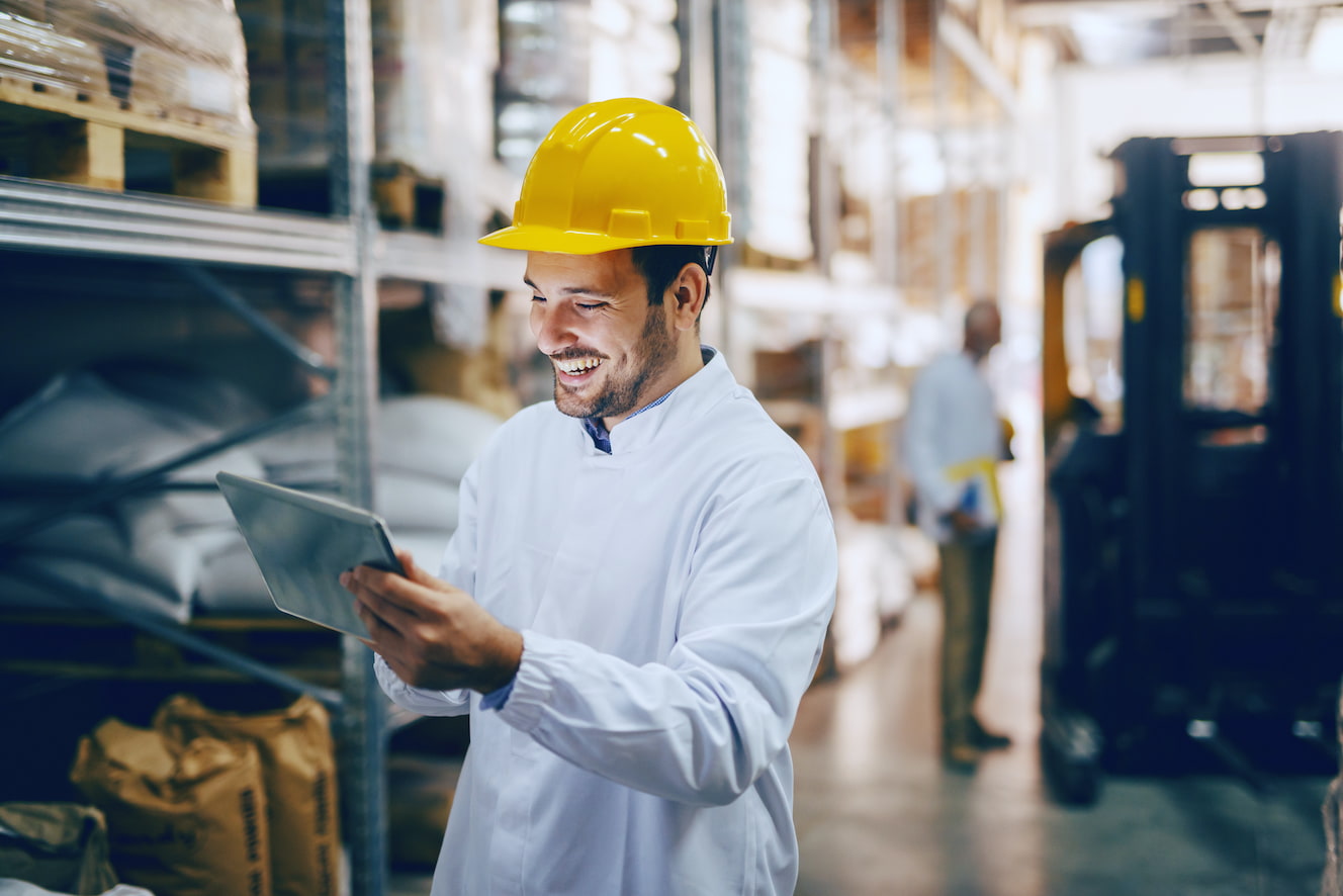 Man with hardhat looking at tablet in warehouse