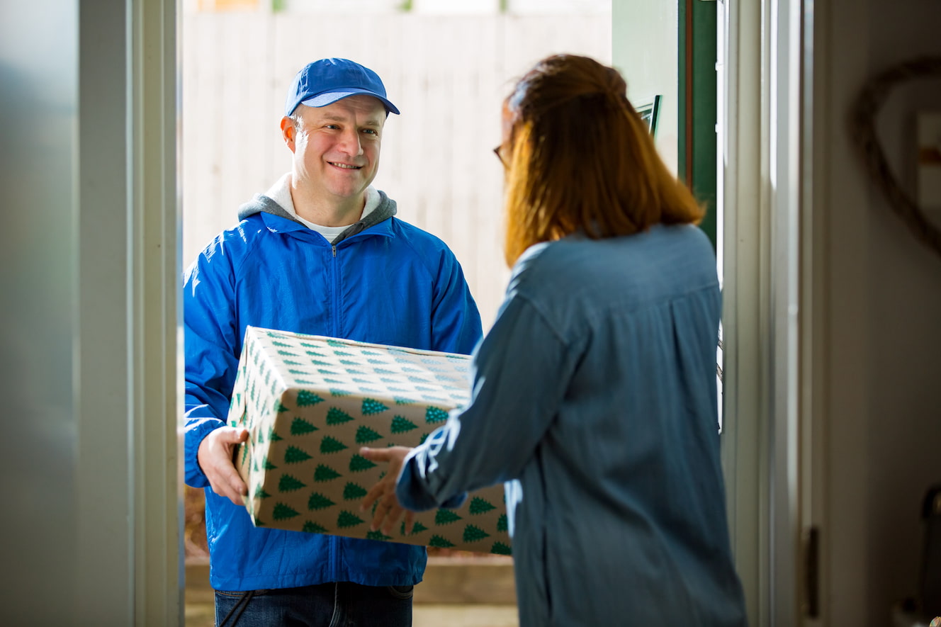 Person delivering wrapped present to front door
