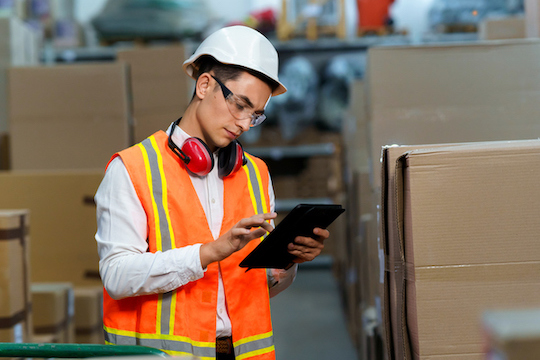 Person Reading Tablet in Warehouse