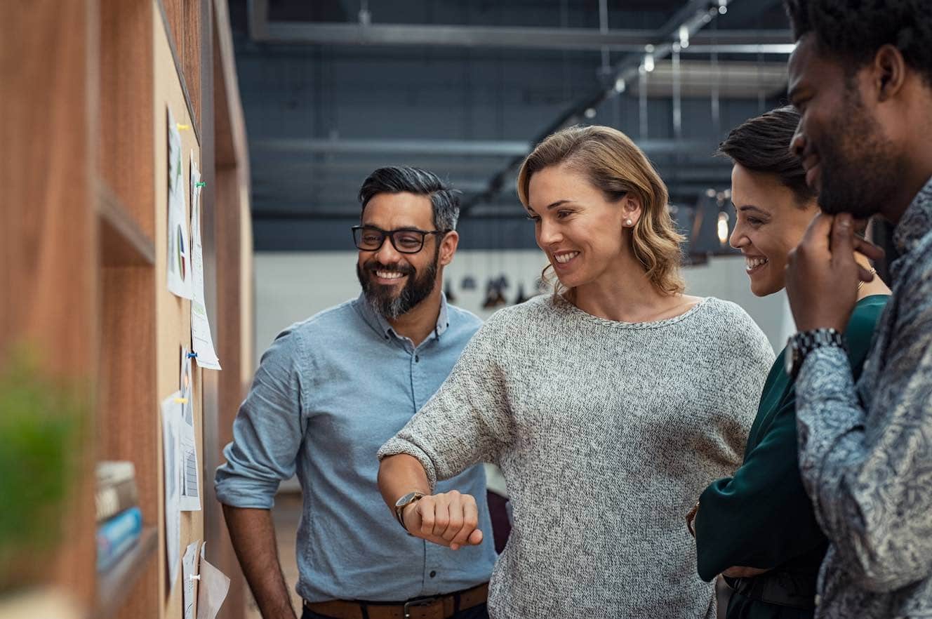 Four people looking at information pinned to a wall