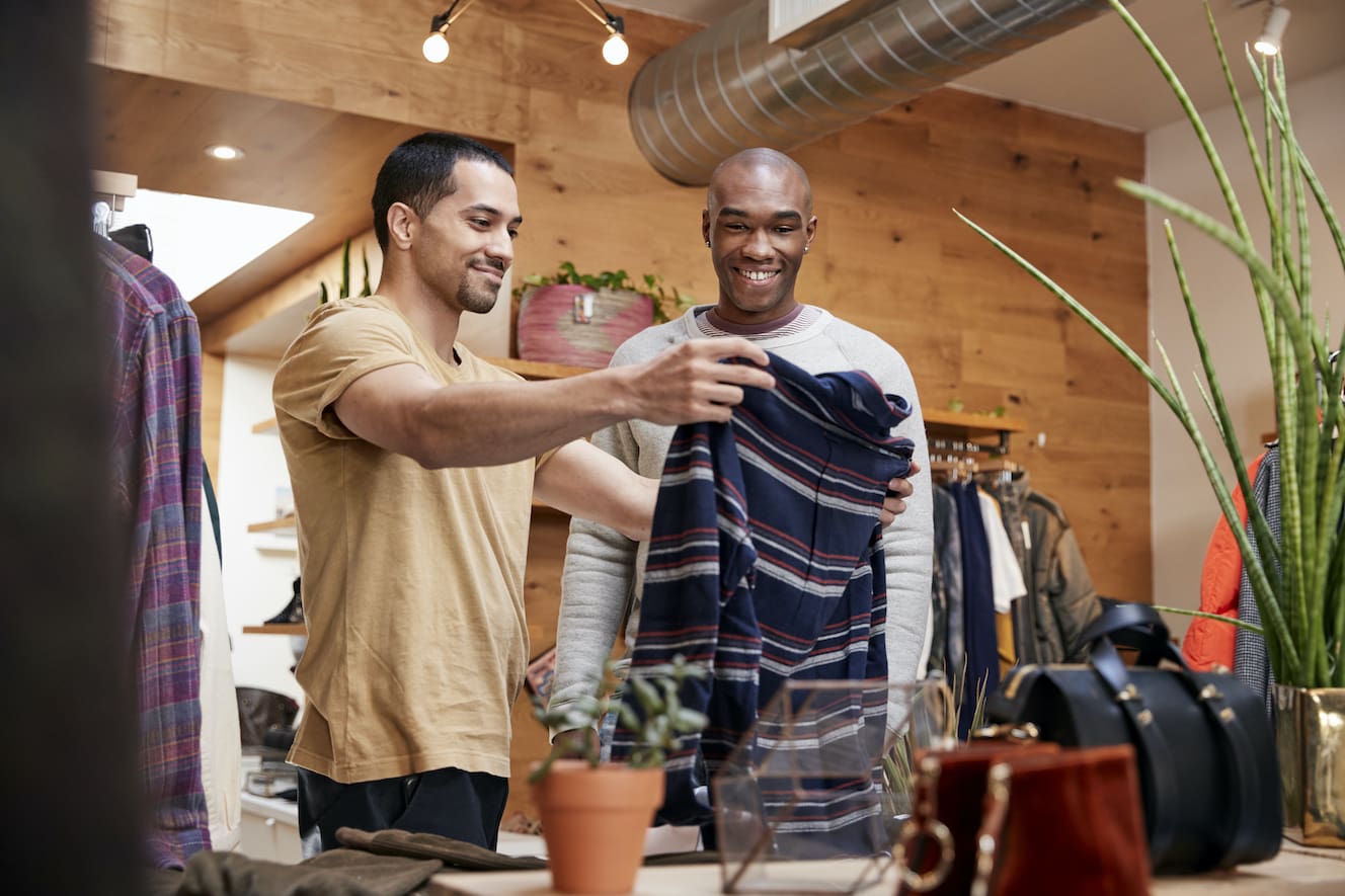 Two People Holding up Clothing in Store