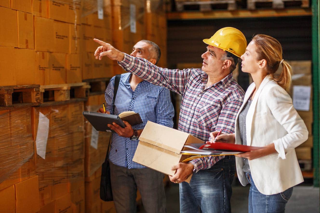 People in warehouse and man in yellow hard hat pointing